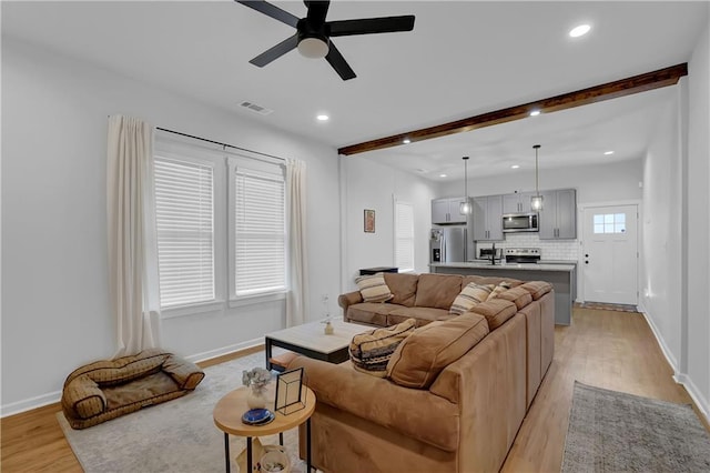 living room featuring beam ceiling, light hardwood / wood-style floors, and ceiling fan