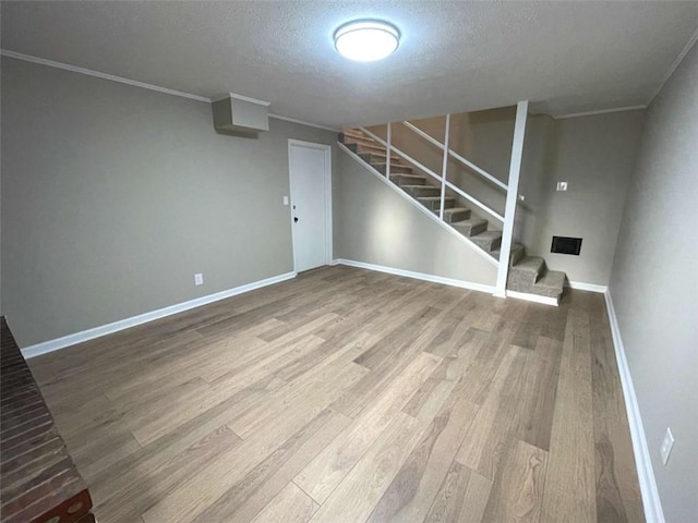 basement with crown molding, hardwood / wood-style flooring, and a textured ceiling