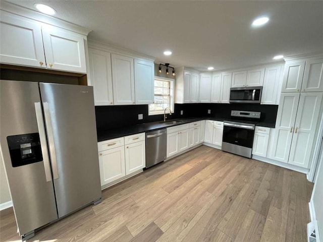 kitchen with stainless steel appliances, sink, white cabinets, and light hardwood / wood-style floors