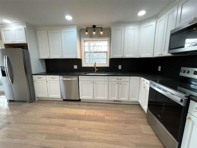 kitchen featuring sink, tasteful backsplash, light hardwood / wood-style flooring, appliances with stainless steel finishes, and white cabinets