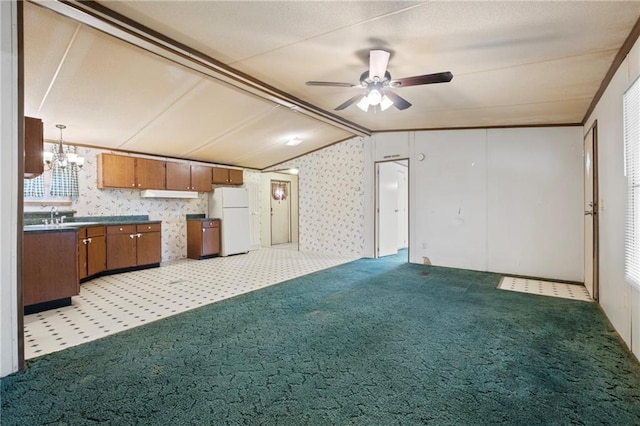 kitchen with brown cabinetry, freestanding refrigerator, vaulted ceiling, dark countertops, and light colored carpet