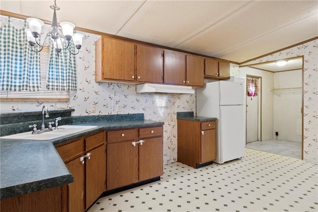 kitchen featuring dark countertops, freestanding refrigerator, brown cabinetry, wallpapered walls, and light floors