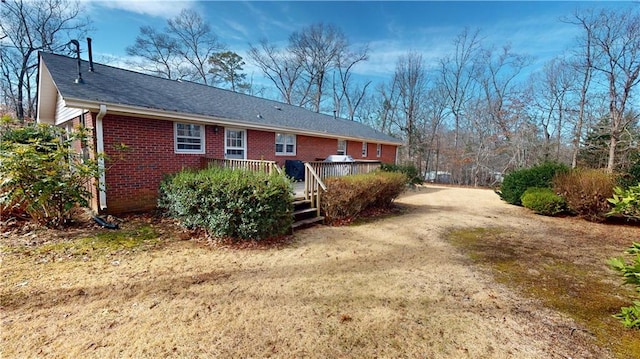 back of house with driveway, a deck, and brick siding