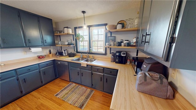 kitchen with a sink, light countertops, stainless steel dishwasher, open shelves, and light wood finished floors