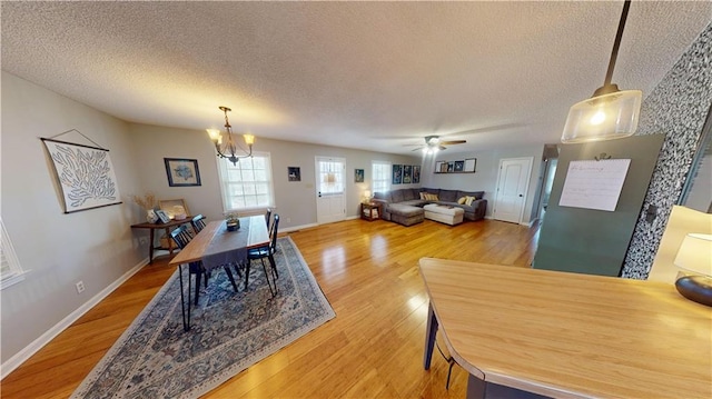 dining room featuring a textured ceiling, ceiling fan with notable chandelier, light wood-style flooring, and baseboards