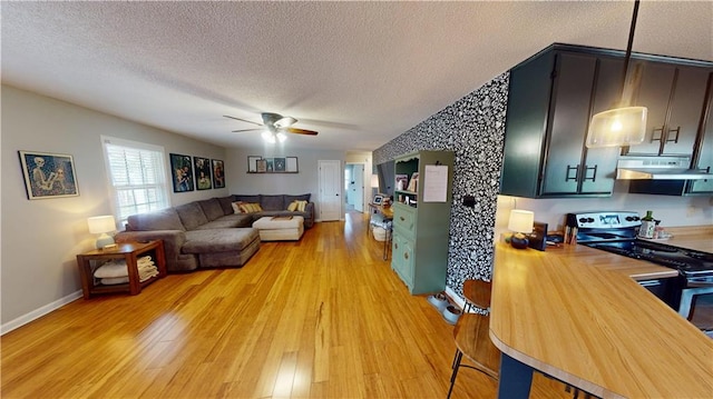 living room featuring light wood-style floors, ceiling fan, a textured ceiling, and baseboards