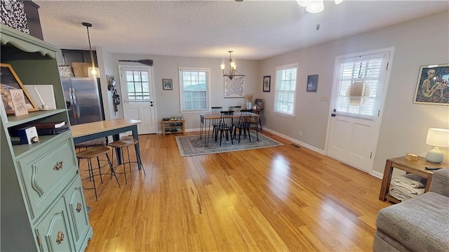 interior space with light wood-style floors, baseboards, a chandelier, and a textured ceiling