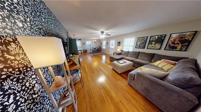 living room with a textured ceiling, ceiling fan, and wood finished floors