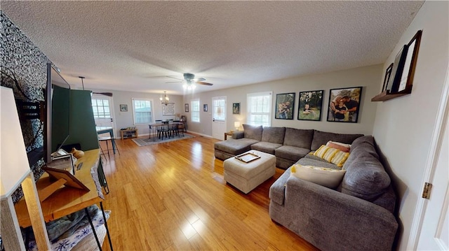 living room featuring light wood finished floors, baseboards, and a textured ceiling