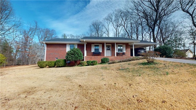 ranch-style home featuring brick siding, driveway, crawl space, a carport, and a front yard