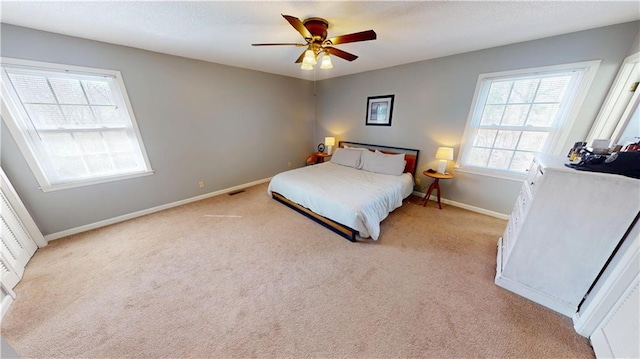 bedroom with a ceiling fan, light carpet, and baseboards