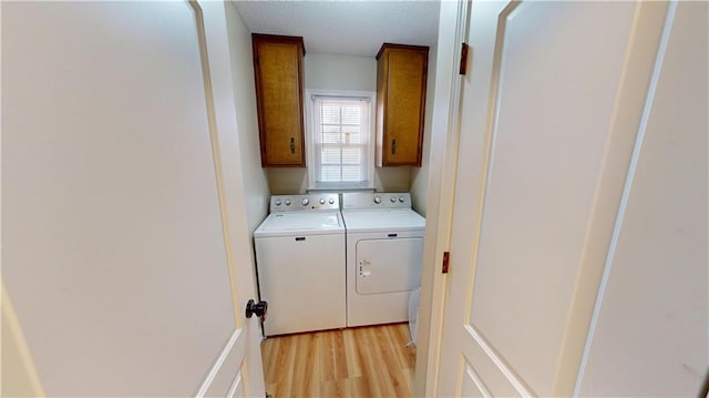 washroom featuring light wood-style floors, cabinet space, independent washer and dryer, and a textured ceiling