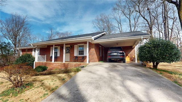 ranch-style house featuring a carport, covered porch, brick siding, and driveway