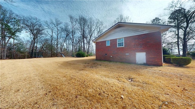 view of property exterior with a trampoline, brick siding, crawl space, and a lawn