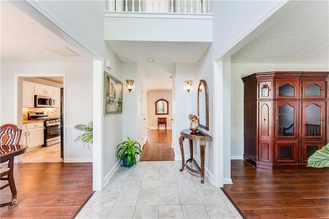 hallway featuring a towering ceiling and light hardwood / wood-style flooring