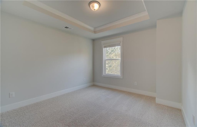 unfurnished room featuring baseboards, visible vents, a tray ceiling, light carpet, and crown molding