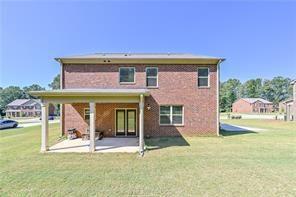 back of property featuring a patio and a lawn