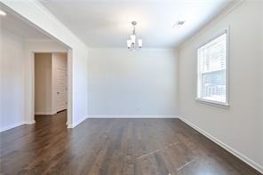 empty room with baseboards, dark wood-style flooring, and a notable chandelier