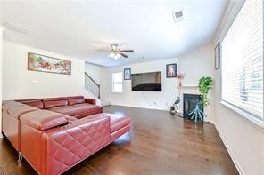 living room featuring stairs, a fireplace, visible vents, and wood finished floors