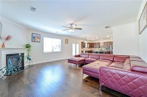 living room with ceiling fan, a fireplace, visible vents, and wood finished floors