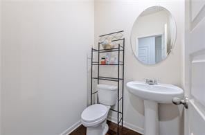 half bathroom with baseboards and toilet