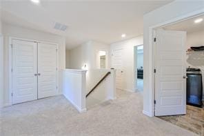 hallway featuring recessed lighting, light colored carpet, and an upstairs landing