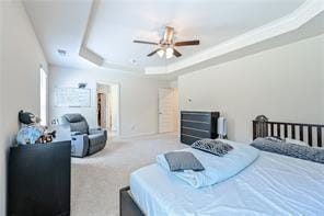 bedroom featuring carpet floors, a tray ceiling, crown molding, and a ceiling fan