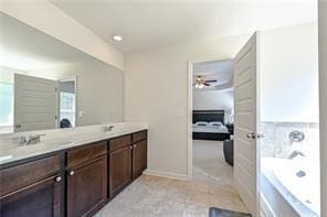 bathroom with ensuite bathroom, a sink, baseboards, a bath, and double vanity