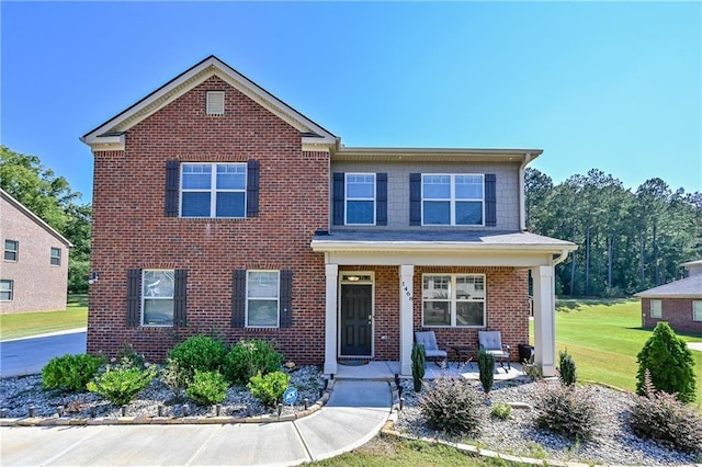 view of front of house featuring a porch, a front yard, and brick siding