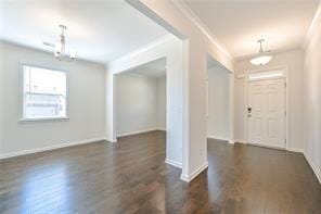 foyer with ornamental molding, dark wood finished floors, and baseboards