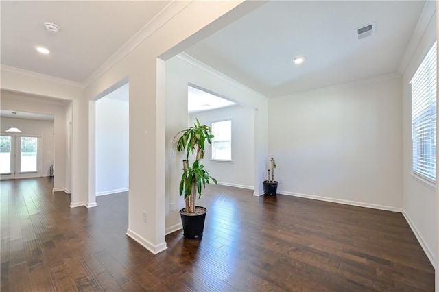 empty room featuring ornamental molding, visible vents, and dark wood finished floors