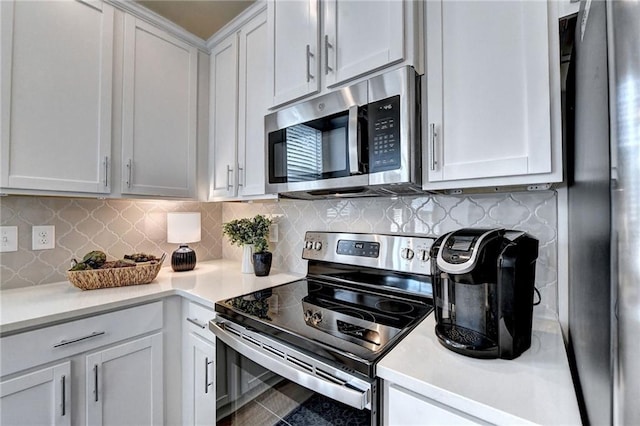 kitchen featuring stainless steel appliances, light countertops, white cabinetry, and decorative backsplash