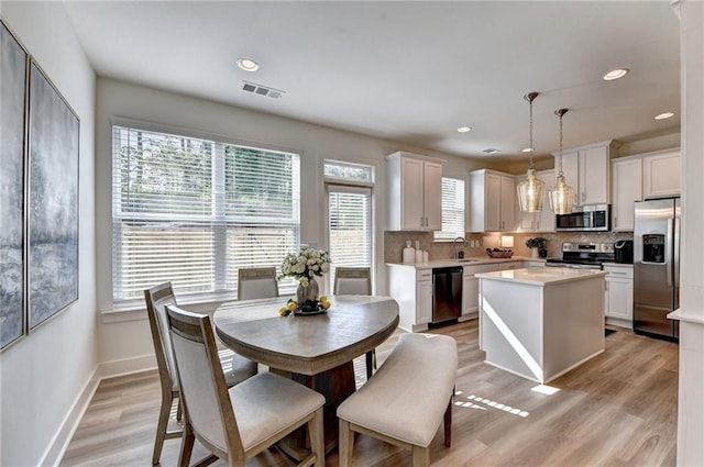 kitchen with visible vents, white cabinets, light countertops, appliances with stainless steel finishes, and decorative light fixtures