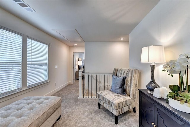 living area featuring light carpet, attic access, visible vents, baseboards, and an upstairs landing