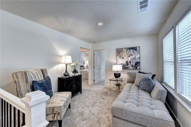 living area with light colored carpet, visible vents, and baseboards