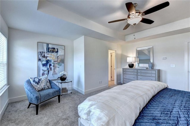 bedroom featuring baseboards, a raised ceiling, a ceiling fan, and light colored carpet