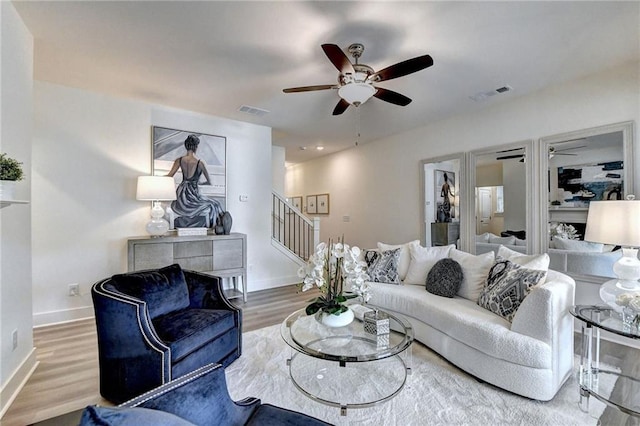 living room with baseboards, stairs, visible vents, and wood finished floors