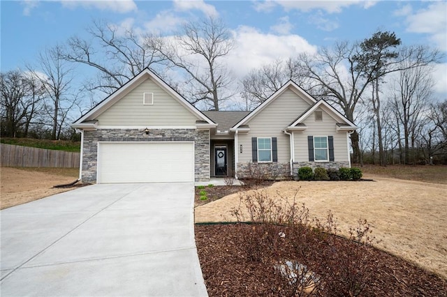 view of front of home featuring a garage, stone siding, fence, and concrete driveway