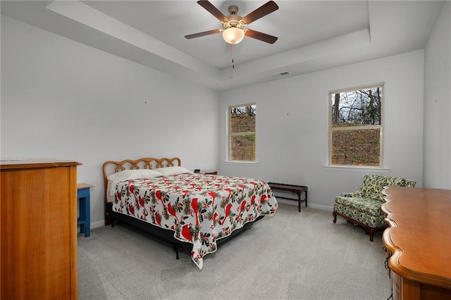 bedroom with a tray ceiling, baseboards, visible vents, and carpet