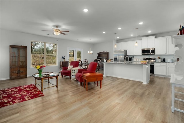 living area with baseboards, a ceiling fan, light wood-style flooring, and recessed lighting