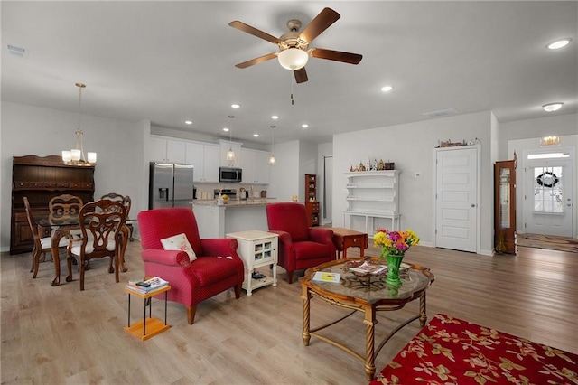 living room featuring light wood finished floors, visible vents, ceiling fan with notable chandelier, and recessed lighting