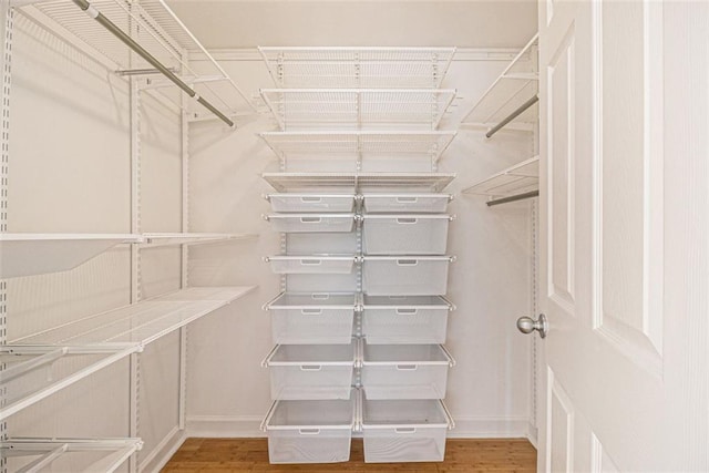 walk in closet with wood finished floors