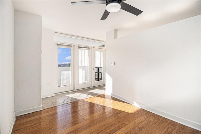 unfurnished room featuring baseboards, wood finished floors, and a ceiling fan