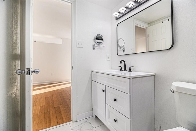 bathroom featuring marble finish floor, toilet, vanity, and baseboards