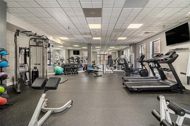 gym featuring a paneled ceiling and baseboards