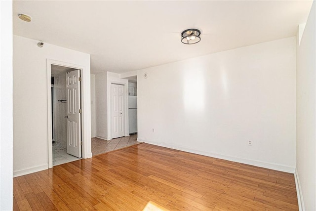 empty room featuring baseboards and light wood finished floors