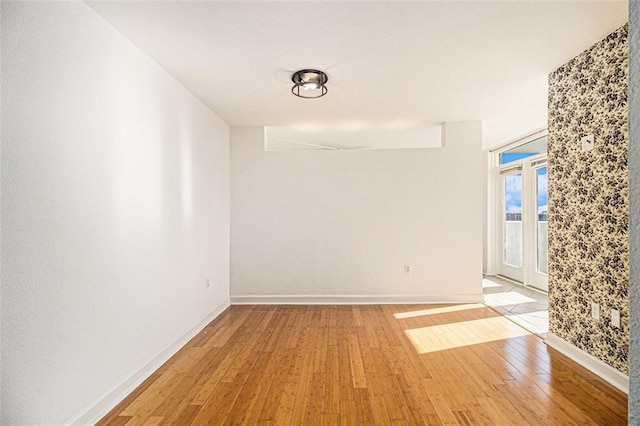 spare room featuring baseboards and light wood-style flooring