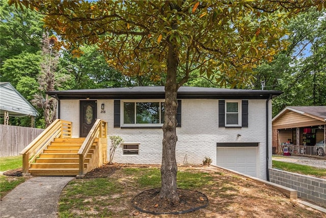 view of front of house featuring a garage, fence, driveway, and brick siding