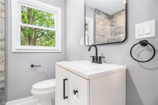 bathroom with toilet, baseboards, and vanity
