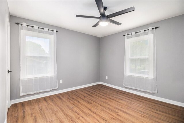 unfurnished room with baseboards, ceiling fan, and a wealth of natural light